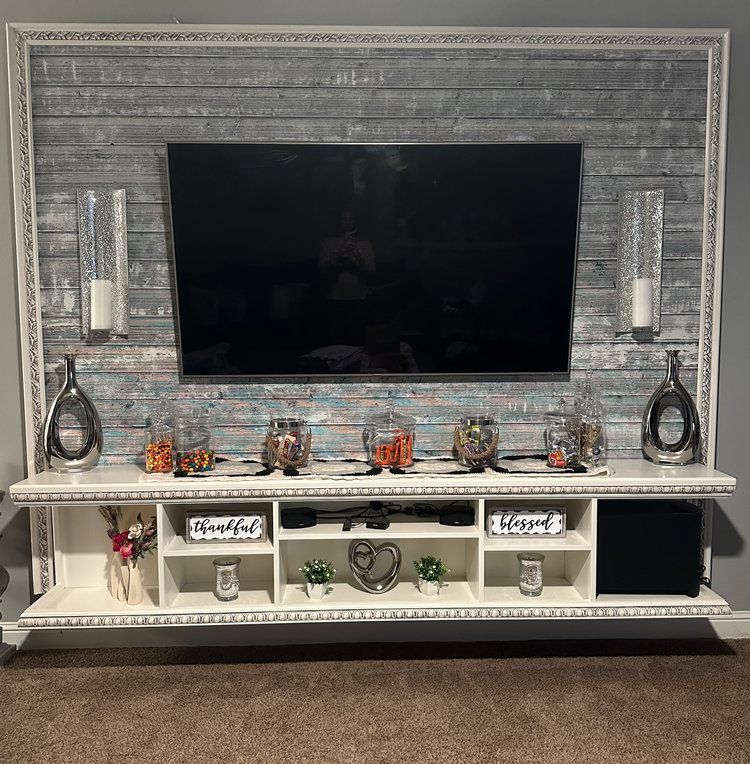 A large flat screen tv is mounted on a wall above a entertainment center.