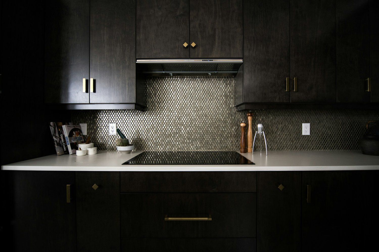 A kitchen with black cabinets and a stove top oven.