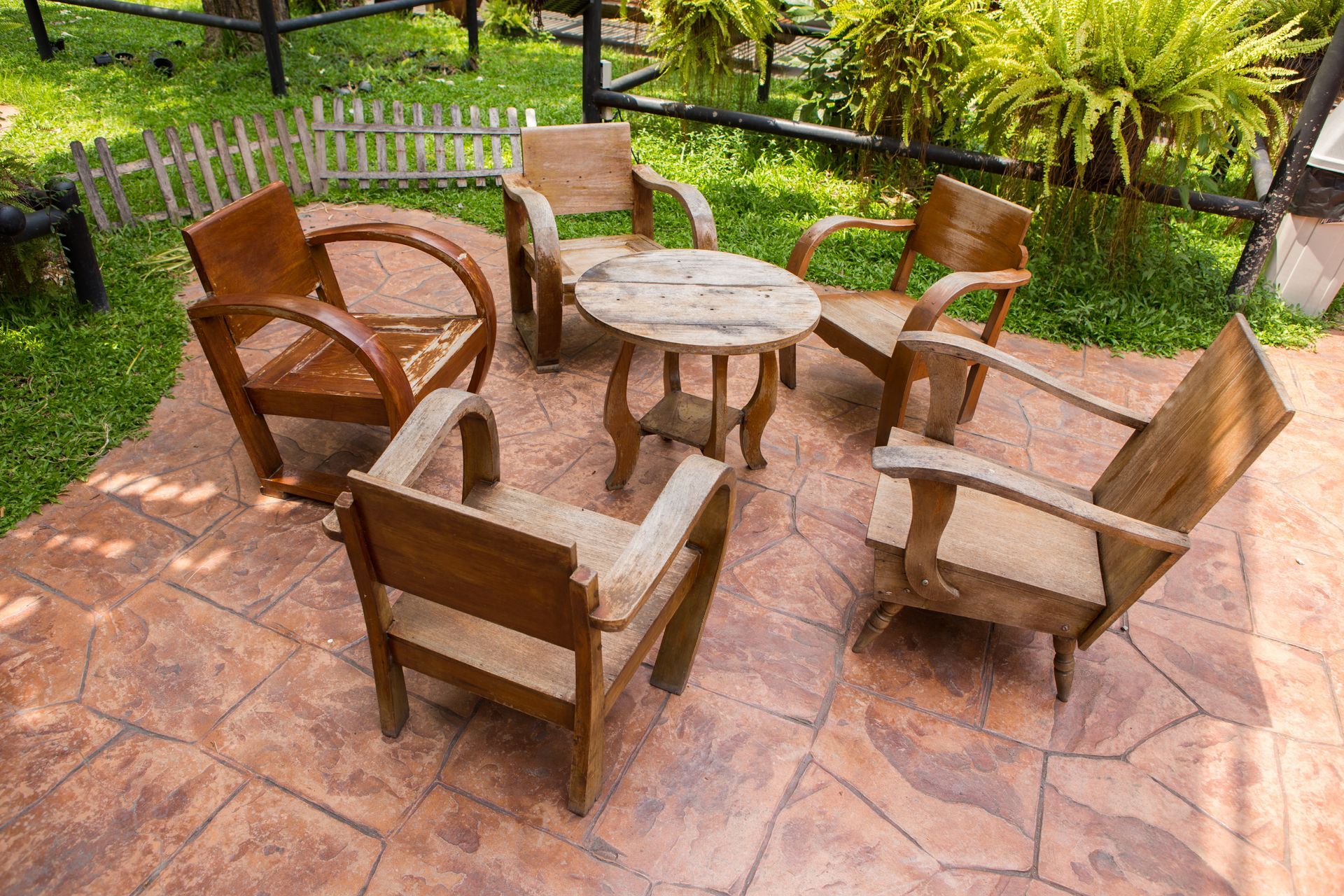 a dyed and stamped concrete patio with rustic wooden chairs and table.