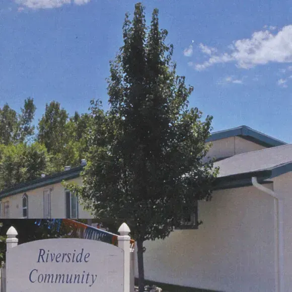 A riverside community sign in front of a house