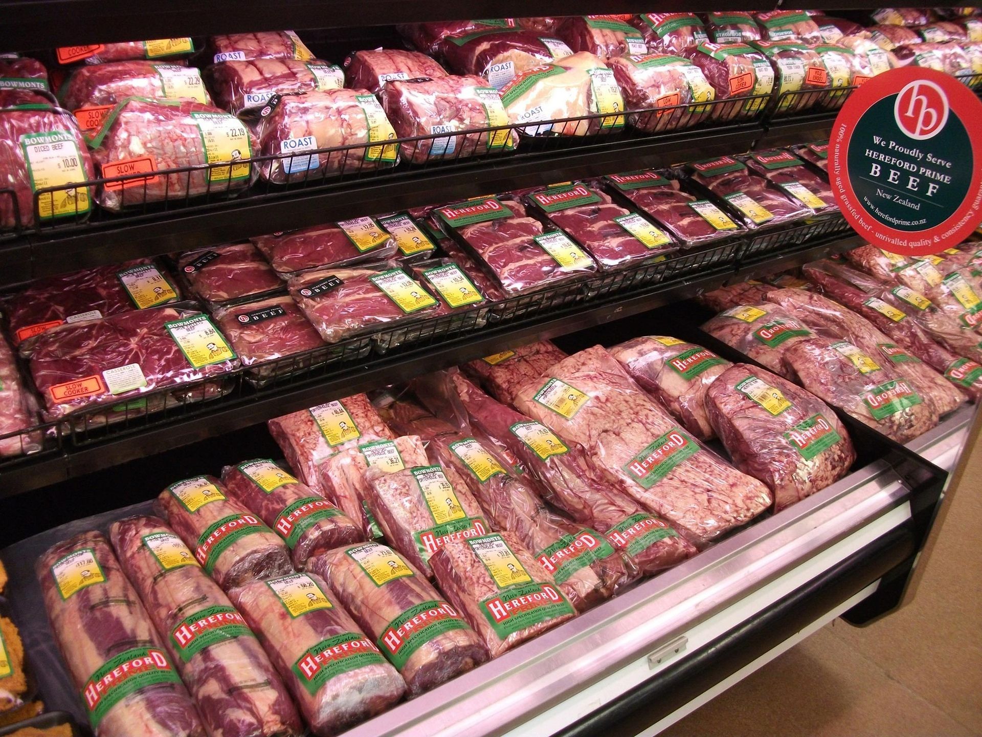 Meat display in a grocery store with various cuts packaged and arranged on shelves.