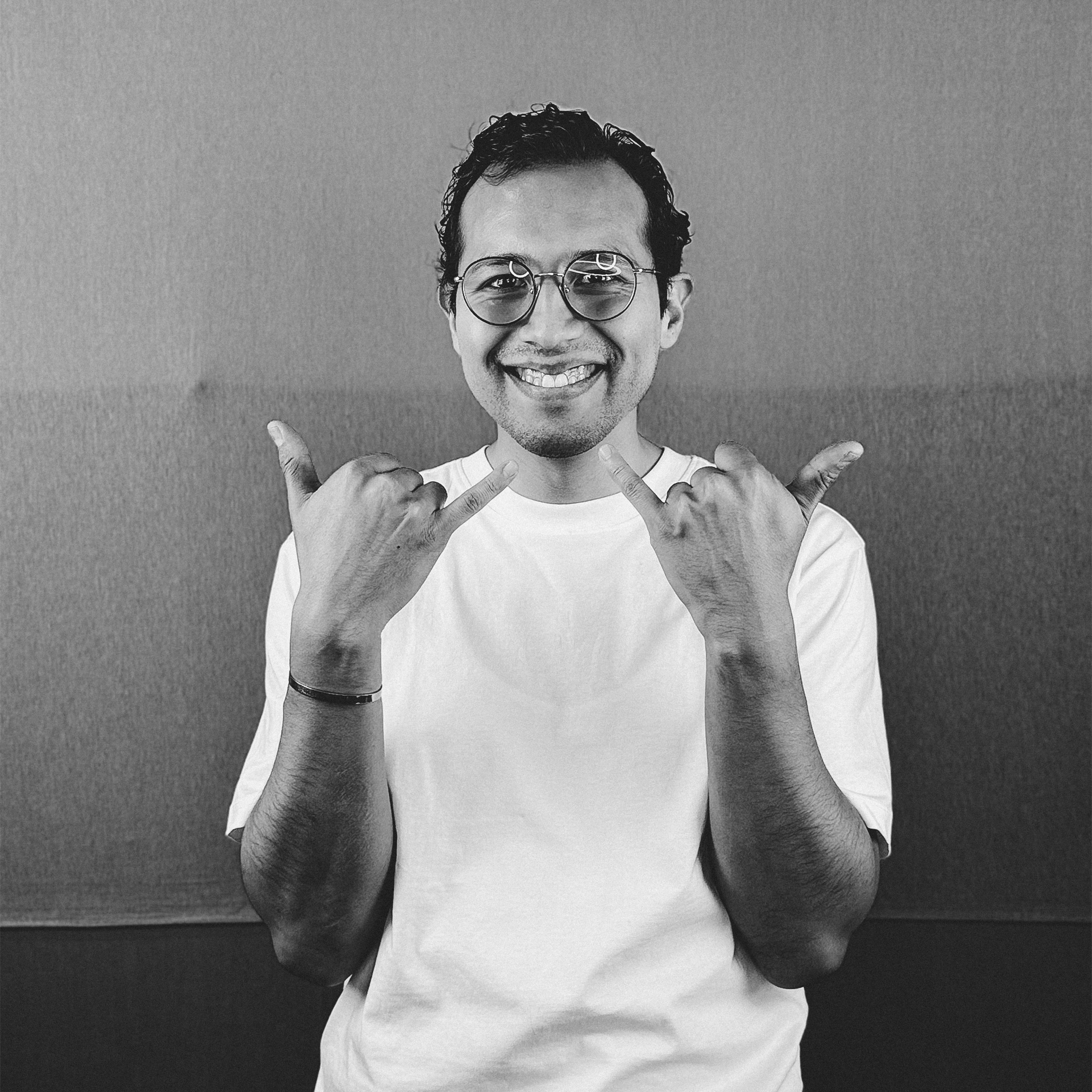 Un hombre con gafas y camisa blanca está haciendo el signo de la paz.