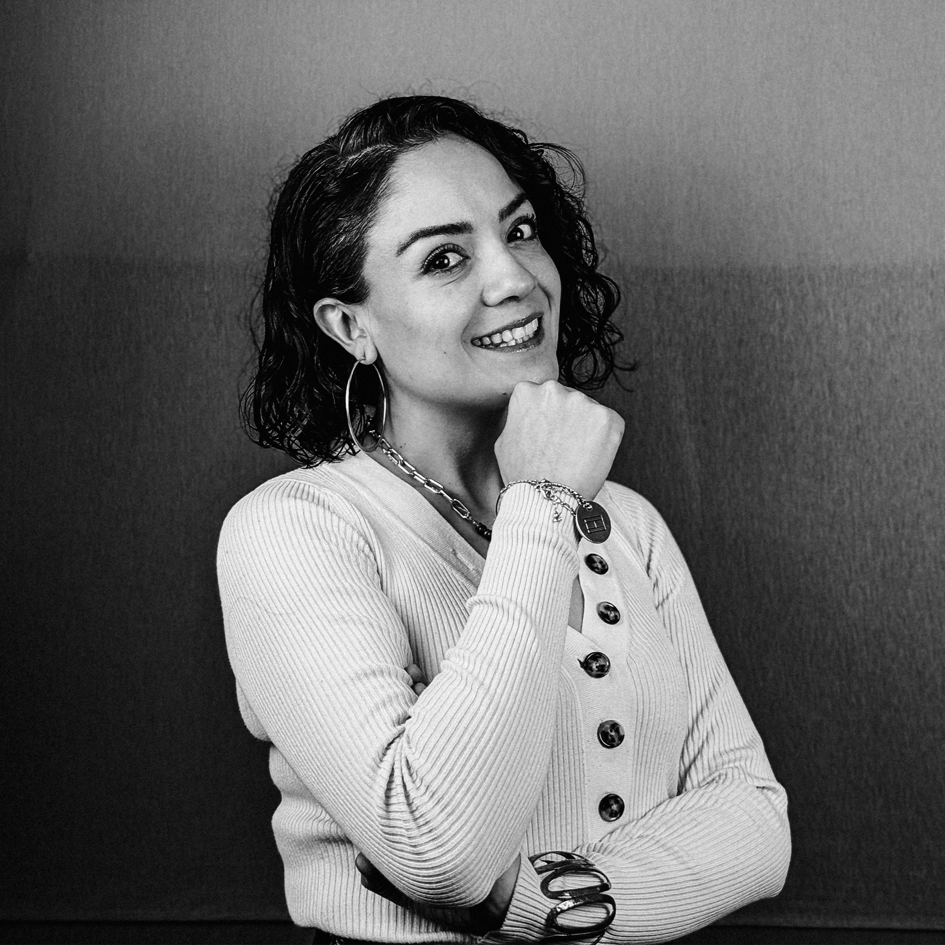 Una fotografía en blanco y negro de una mujer sonriendo con la mano en la barbilla.