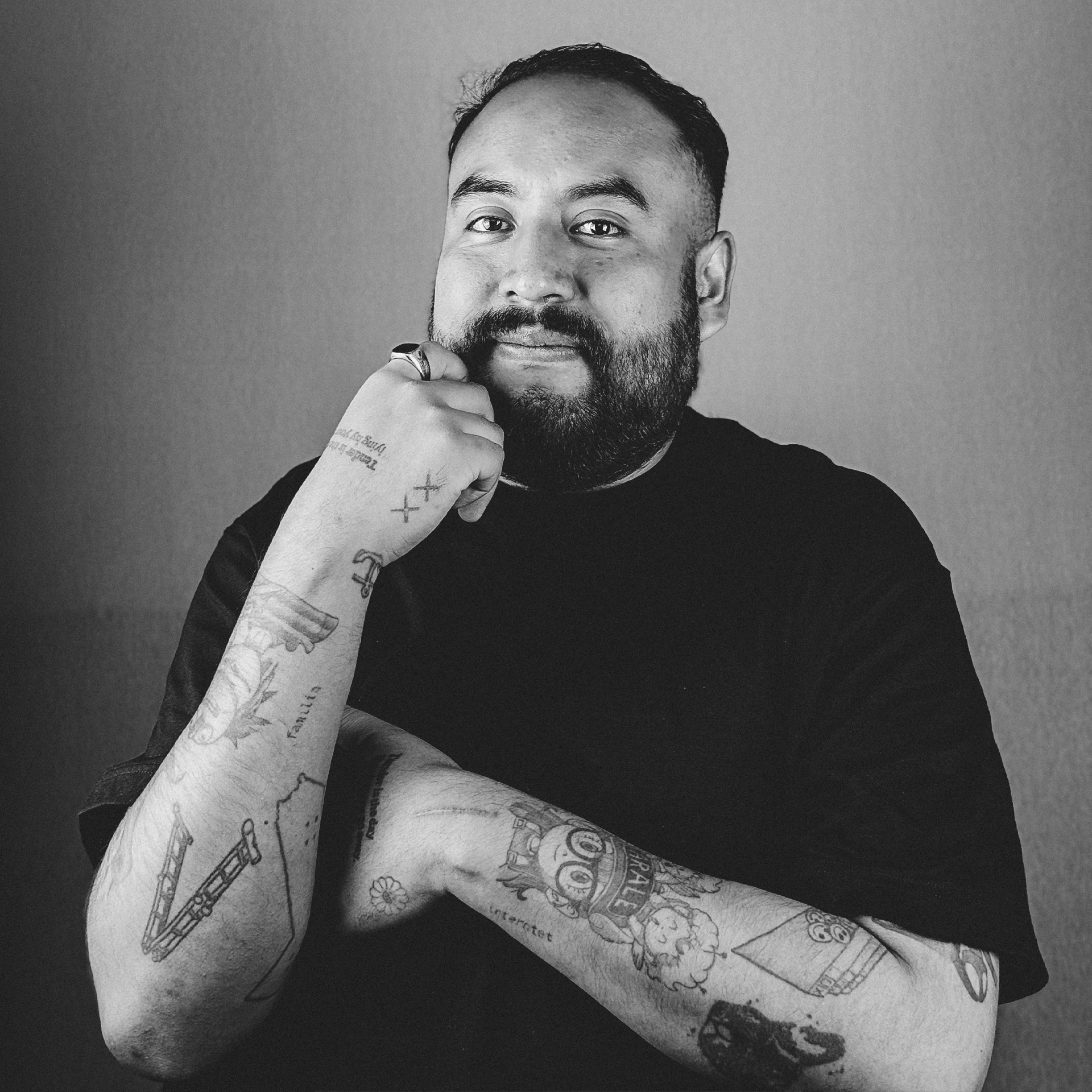 Una fotografía en blanco y negro de un hombre con tatuajes en los brazos.