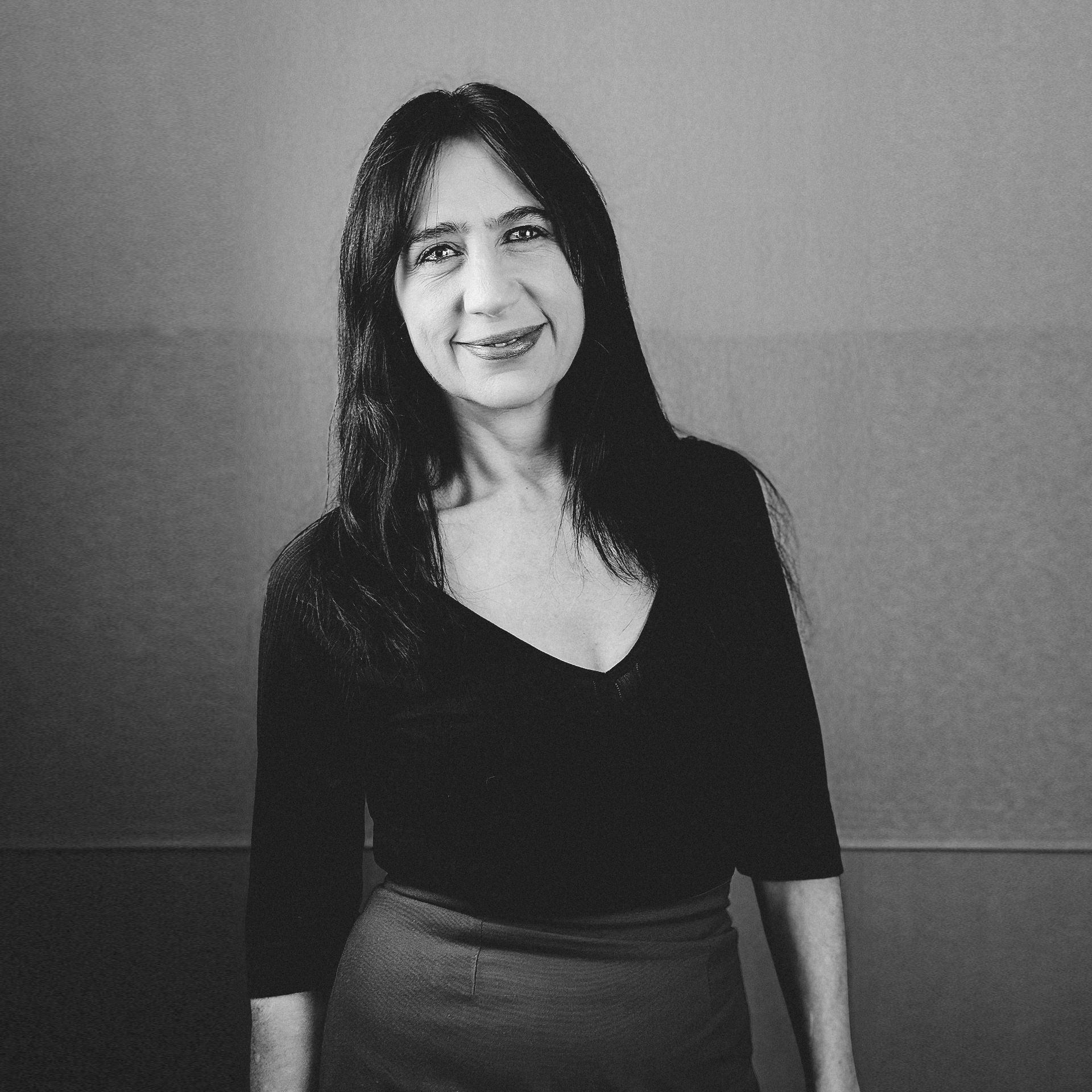 Una mujer con cabello largo sonríe en una foto en blanco y negro.