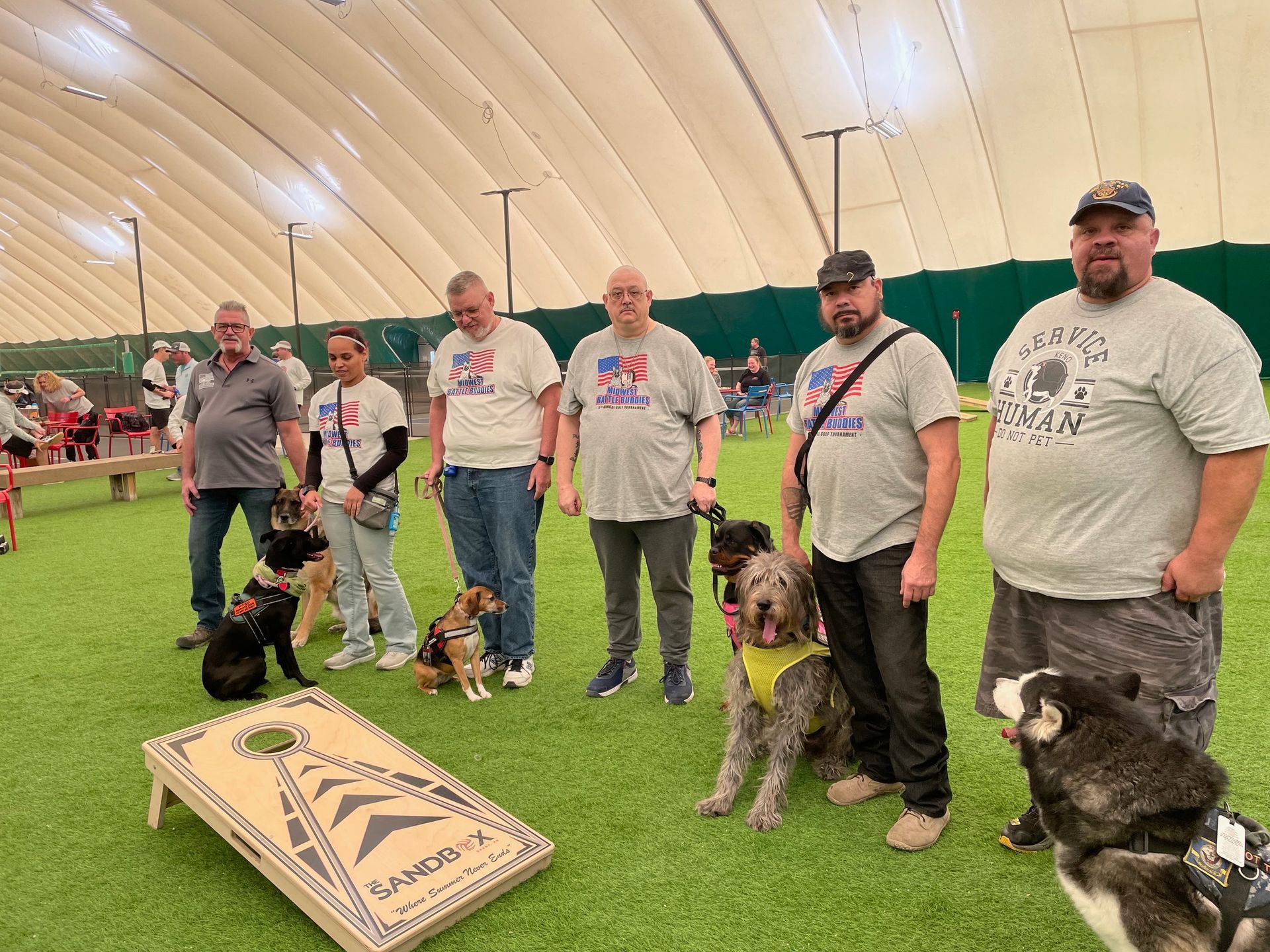 Veterans and their service dogs pose at a cornhole tournament.