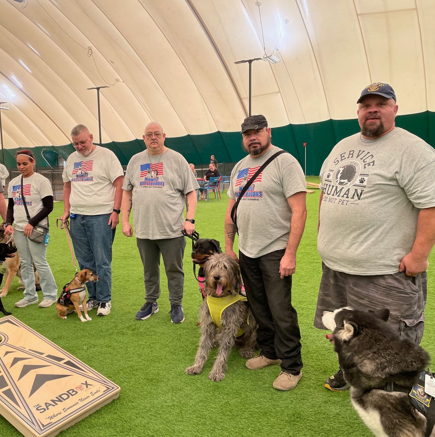 Veterans and their service dogs pose at a cornhole tournament.
