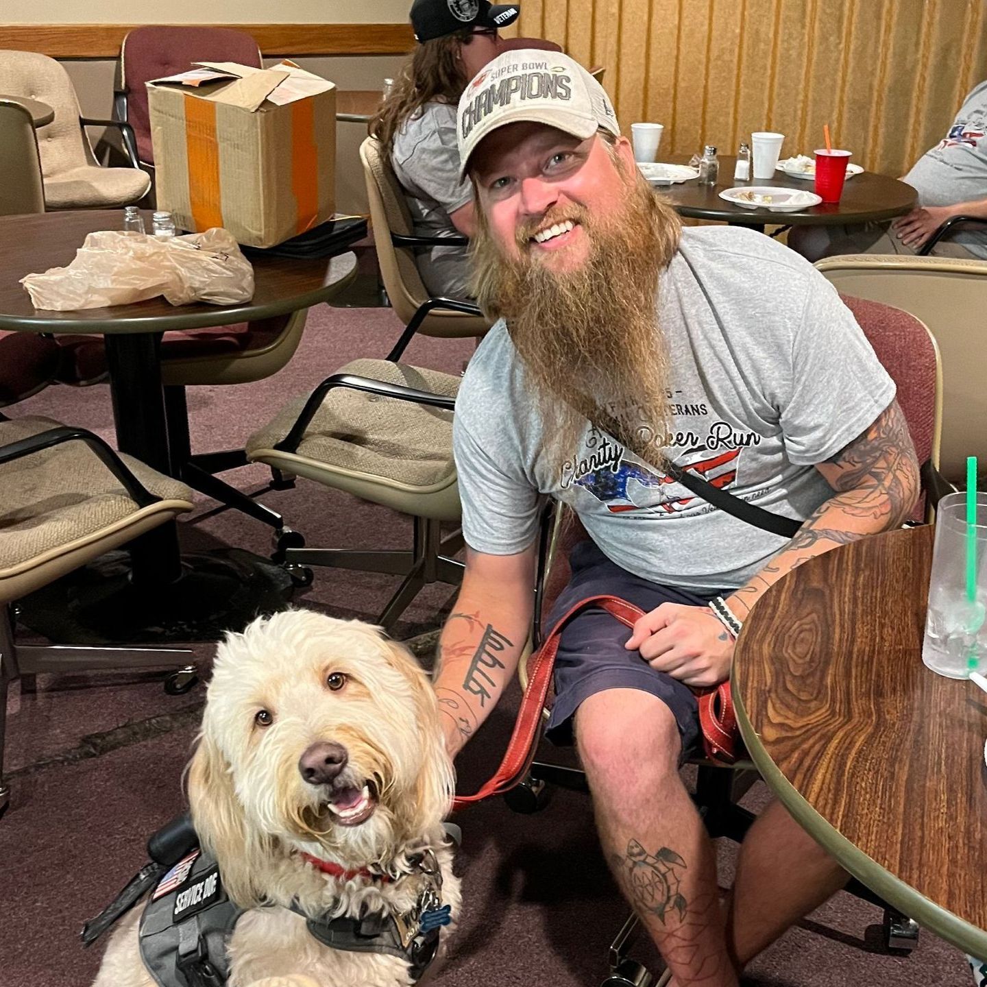 A smiling veteran pets his dog