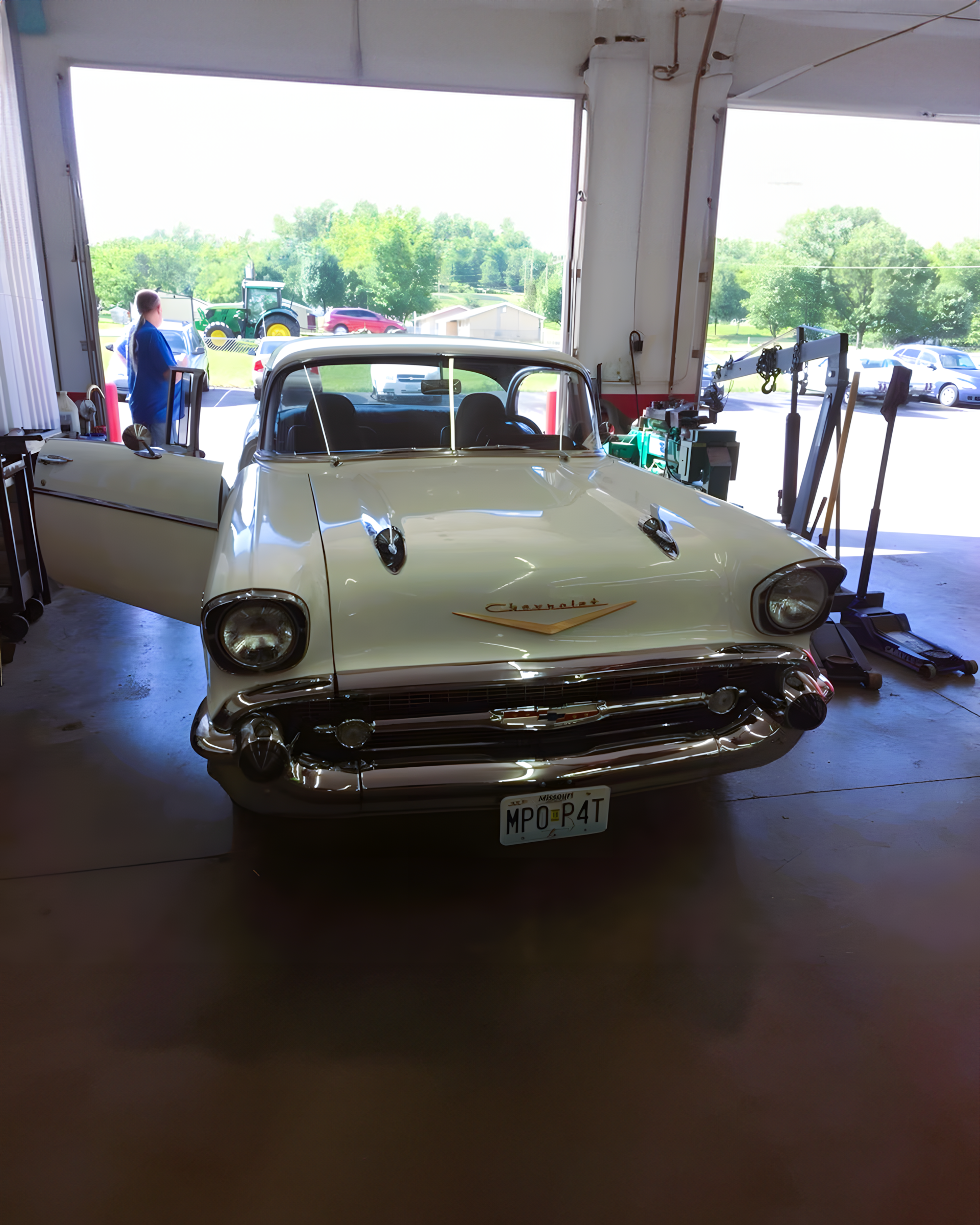 White 1957 Chevrolet Bel Air coupe with door open in a garage. | C & C Auto
