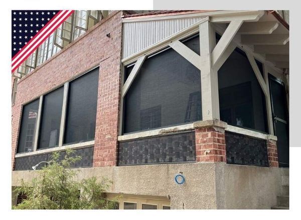 Exterior of a brick building with black shades on the windows. An American flag is visible in the top left corner.