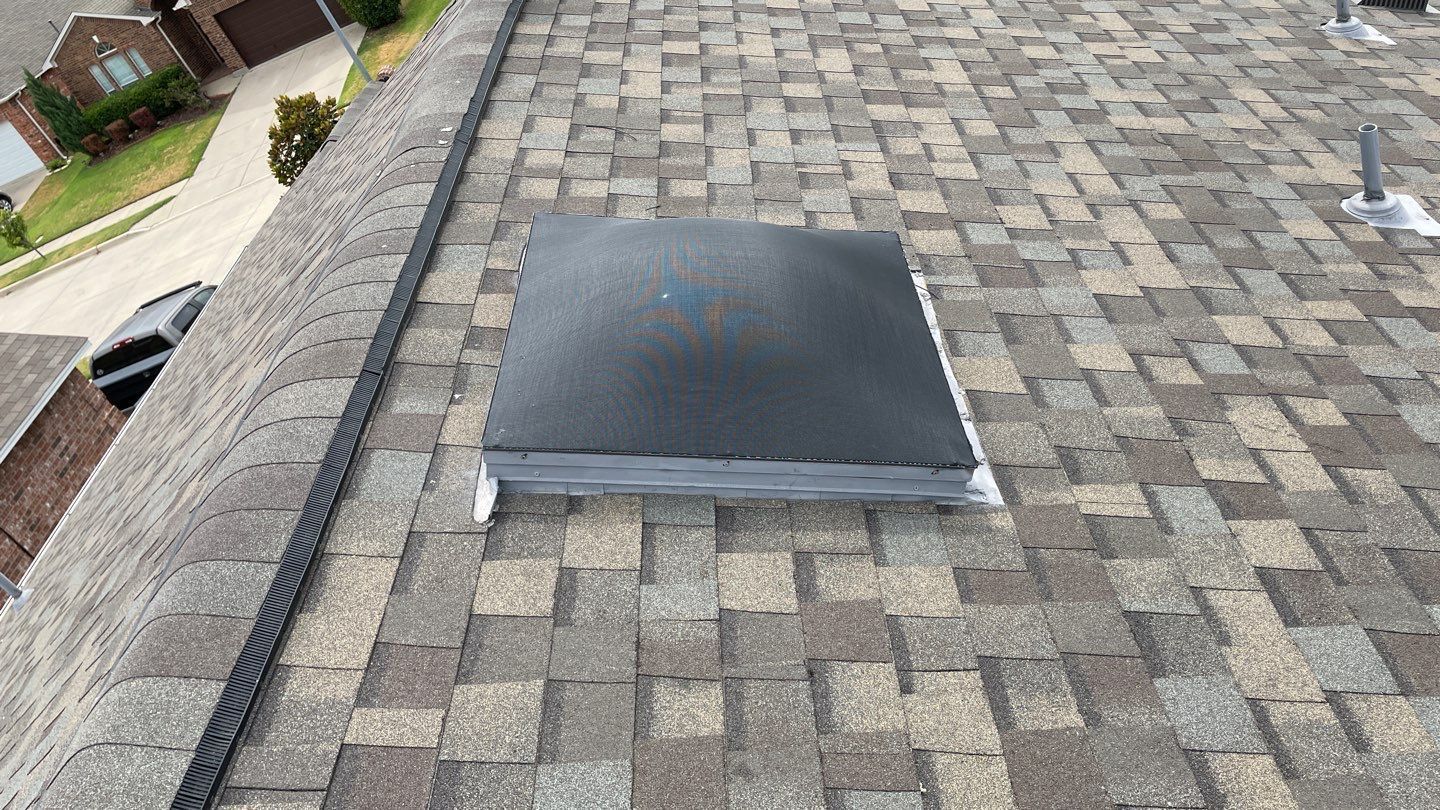 Gray shingle roof with a black, square vent in the center.