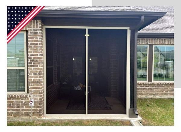 Screened-in patio with a brown frame and dark mesh. The space is between a brick wall and the house's exterior.