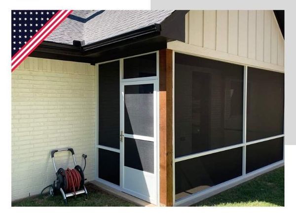 Screened-in porch attached to a brick home.  White frames, black screens, door, and a hose reel are visible.