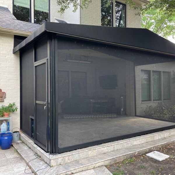 Black-framed screened porch with a door and steps leading up to it. The porch covers a concrete patio outside a house.
