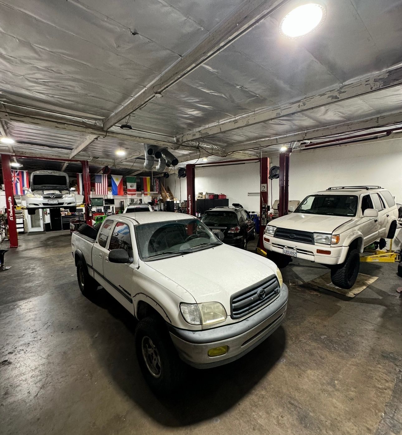 White Toyota pickup and SUV in a well-lit auto repair shop | FNP Auto