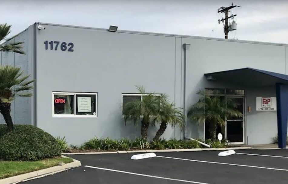 Rear view of a light gray Dodge Challenger with black racing stripes | FNP Auto