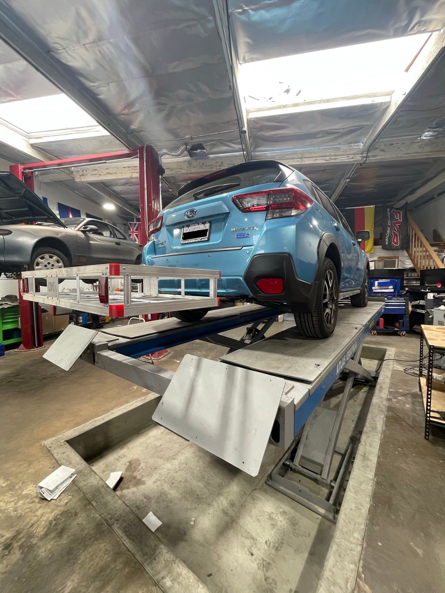 A light blue Subaru Crosstrek on a car lift in a repair shop | FNP Auto