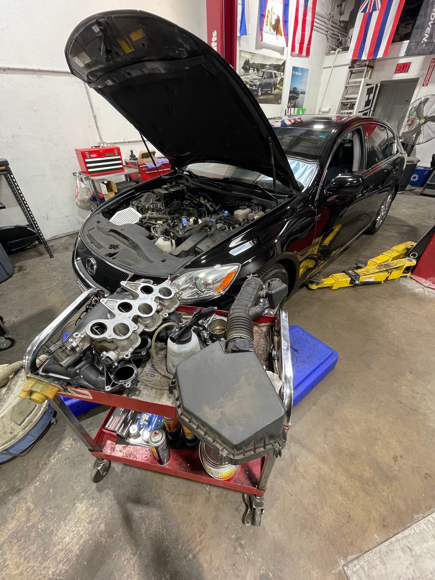 Black car with open hood, engine components on a cart in a shop | FNP Auto