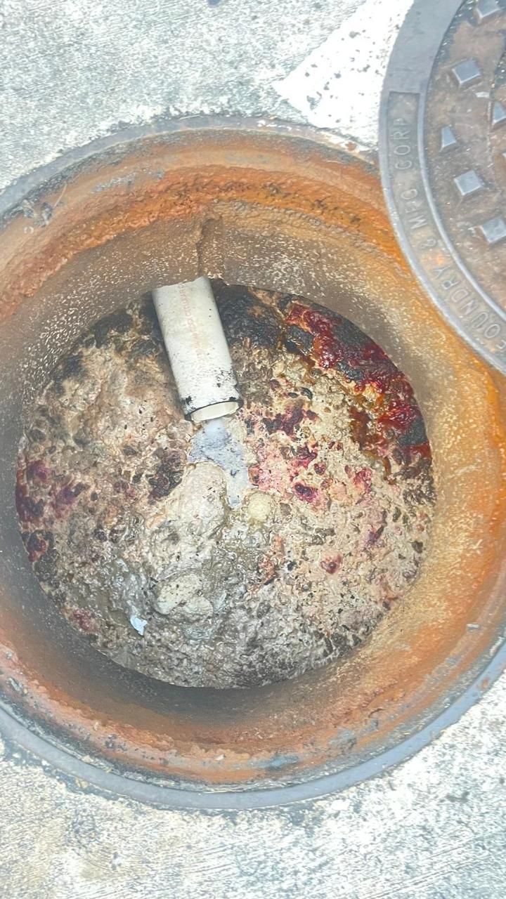 A close up of a manhole cover with a spoon in it.