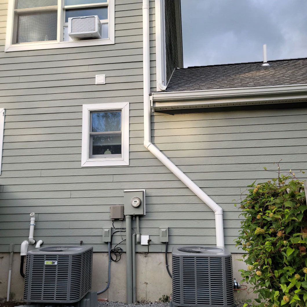 There are two air conditioners on the side of a house.