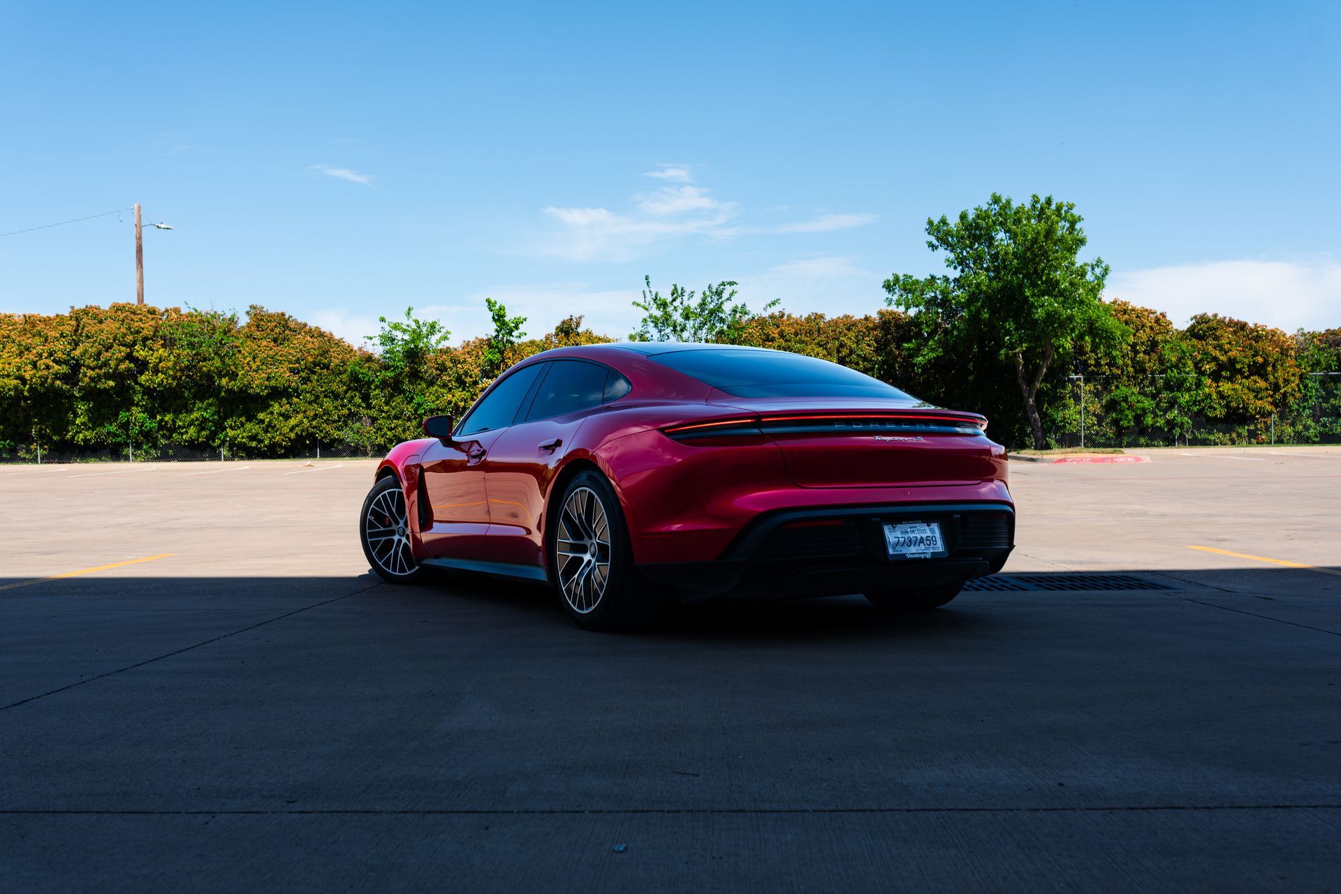 A red porsche taycan is parked in a parking lot.