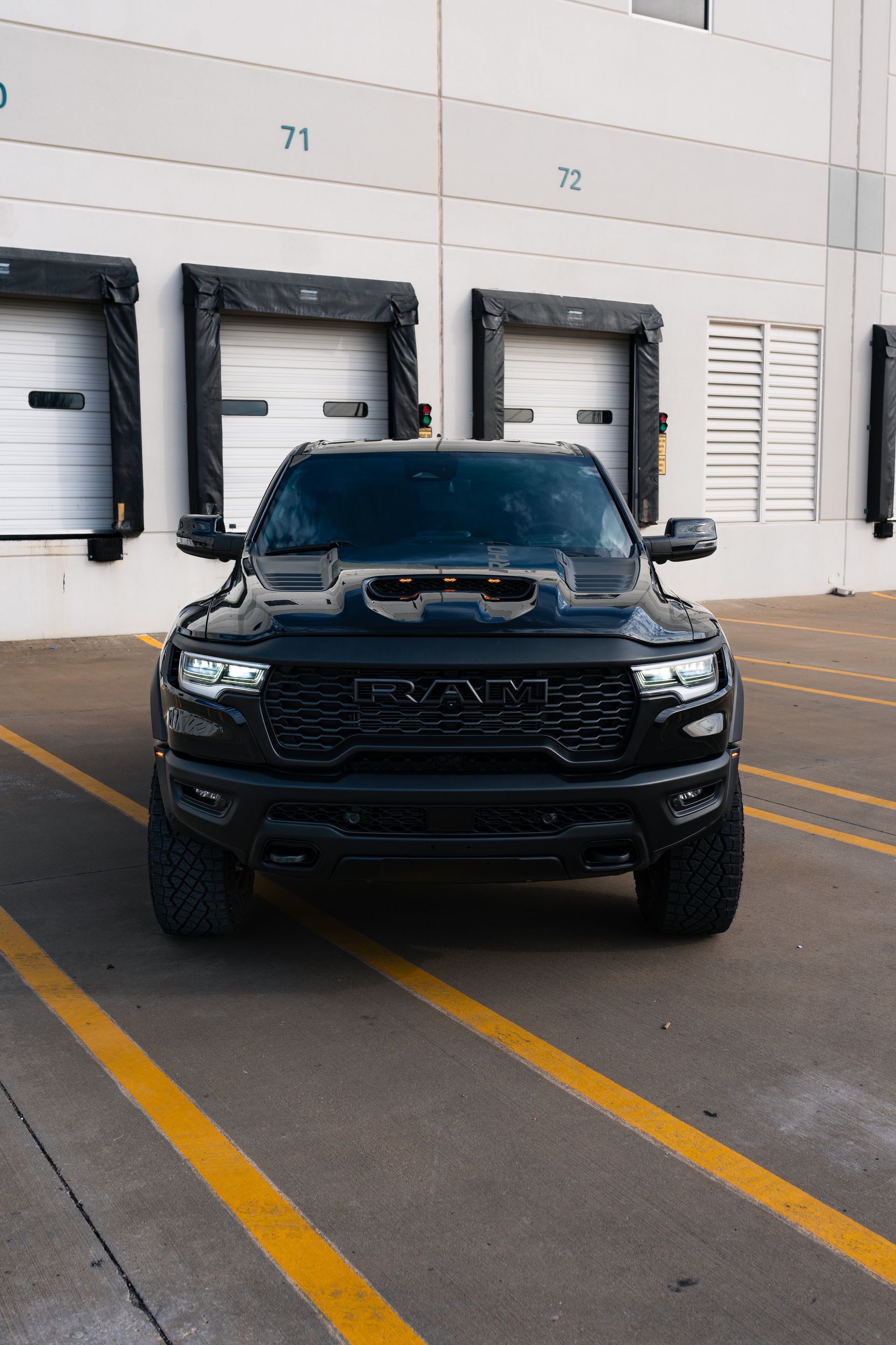 A black truck is parked in a parking lot in front of a building.
