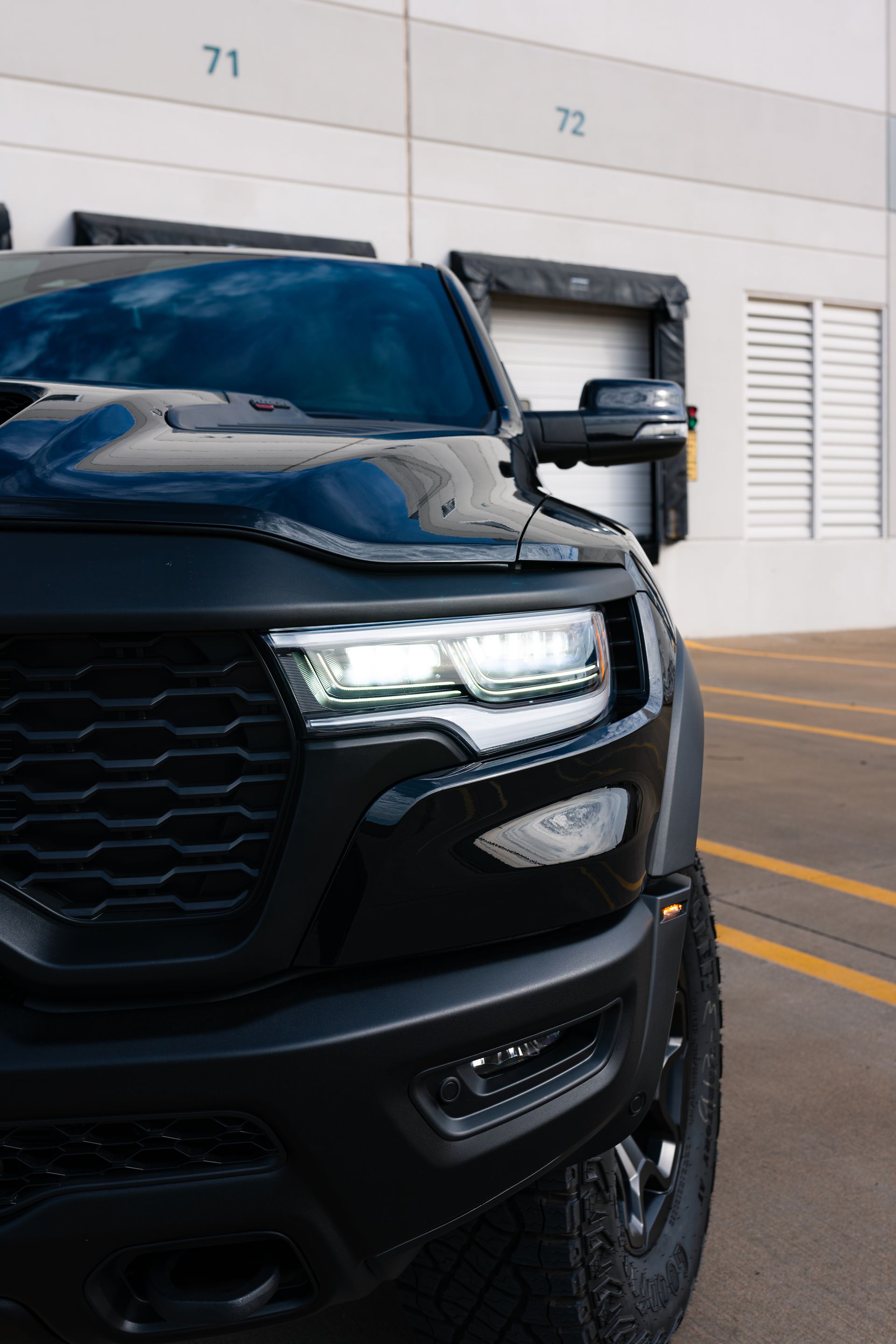 A black truck is parked in a parking lot in front of a building.