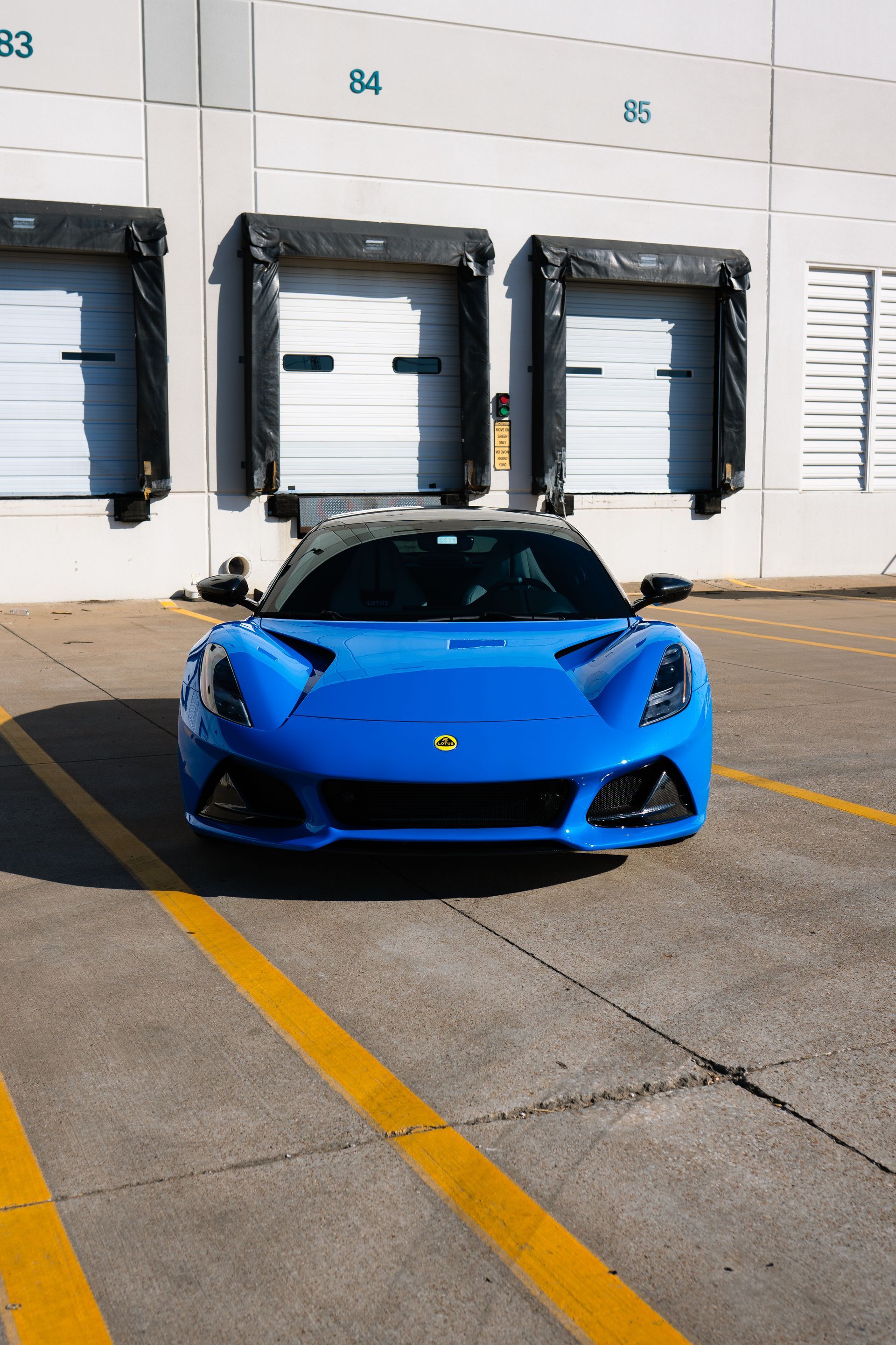 A blue sports car is parked in a parking lot in front of a building.
