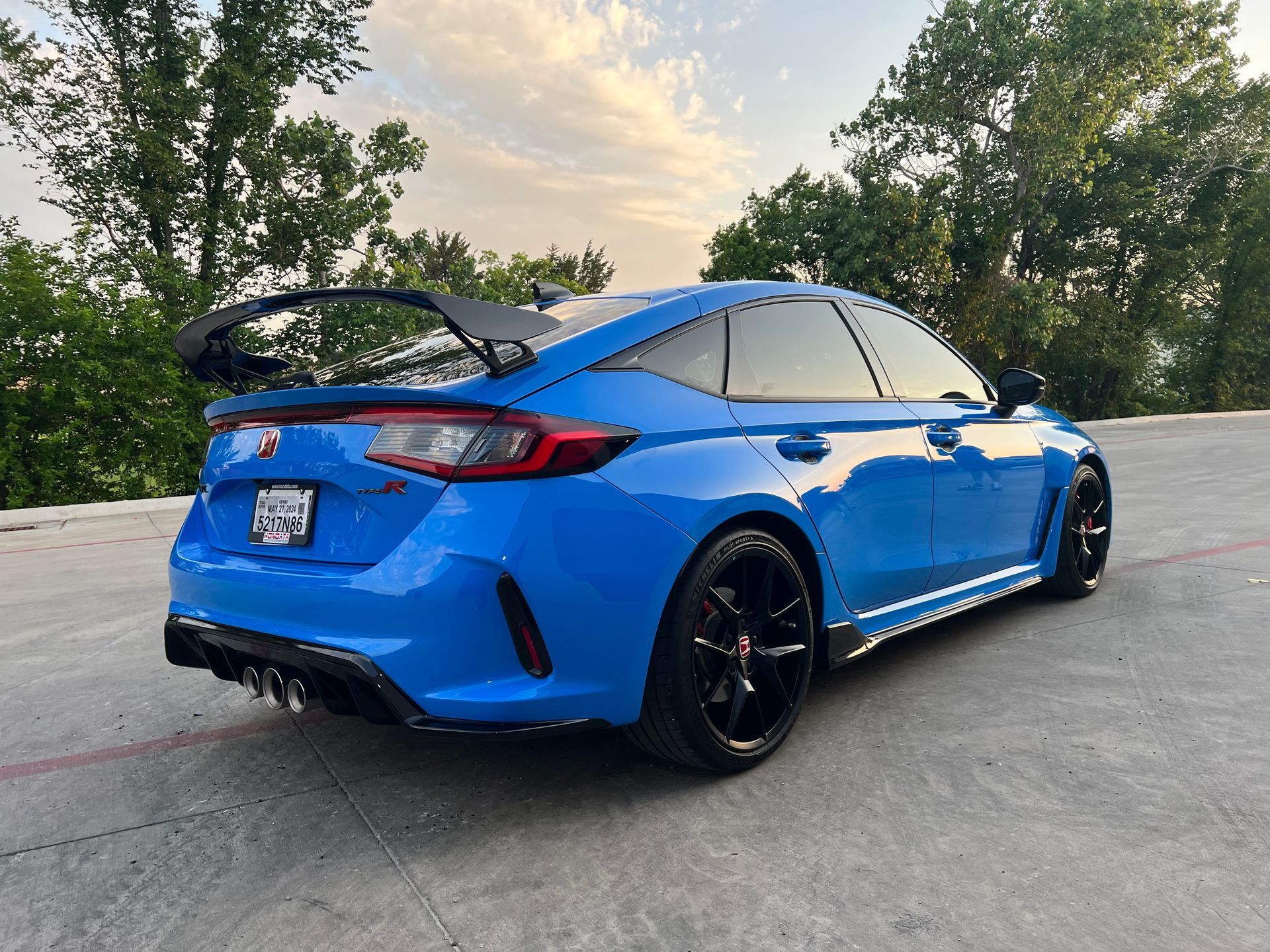 A blue car with a spoiler is parked on the side of the road.