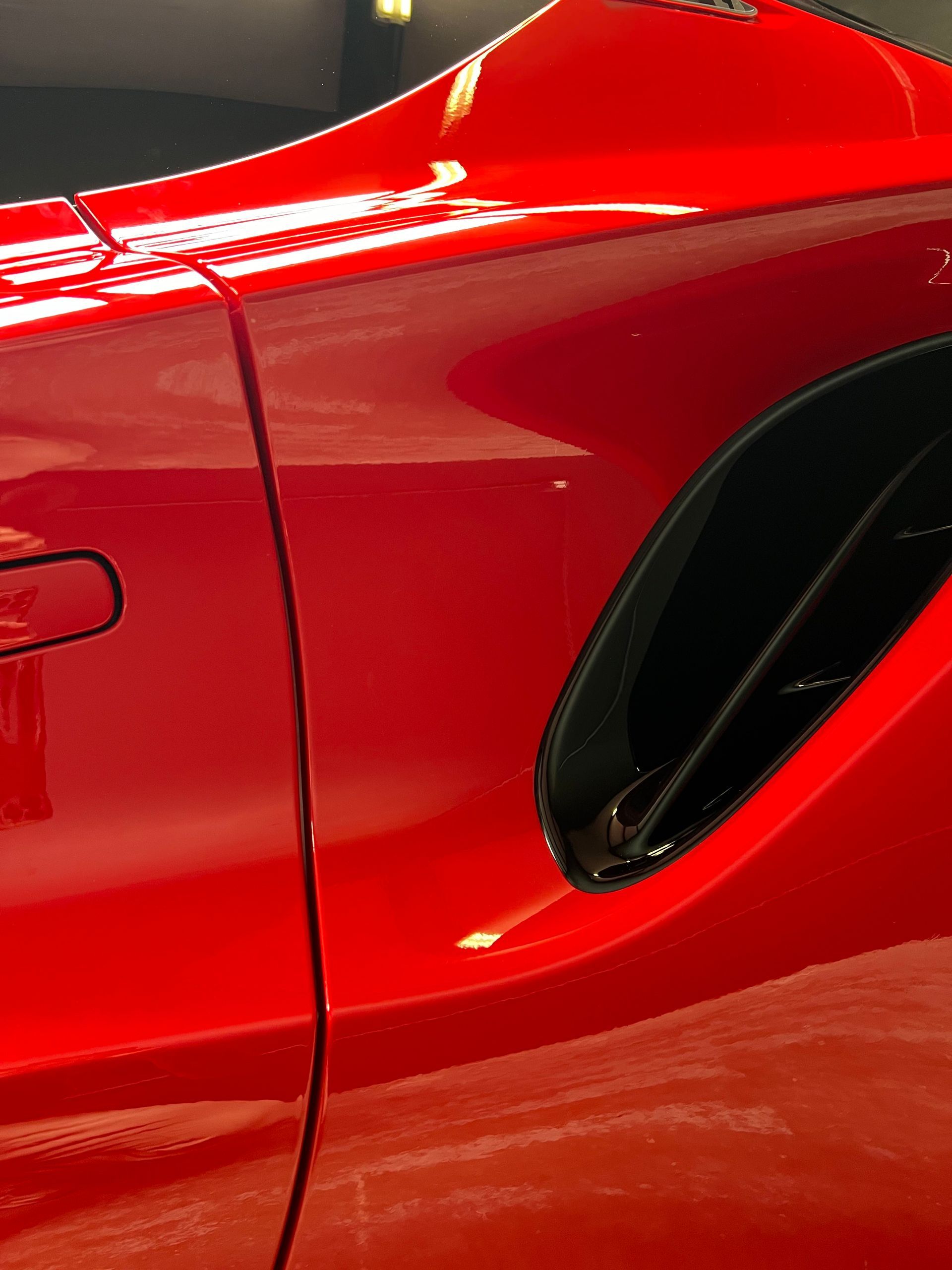 A red sports car is parked in a garage with the door open.
