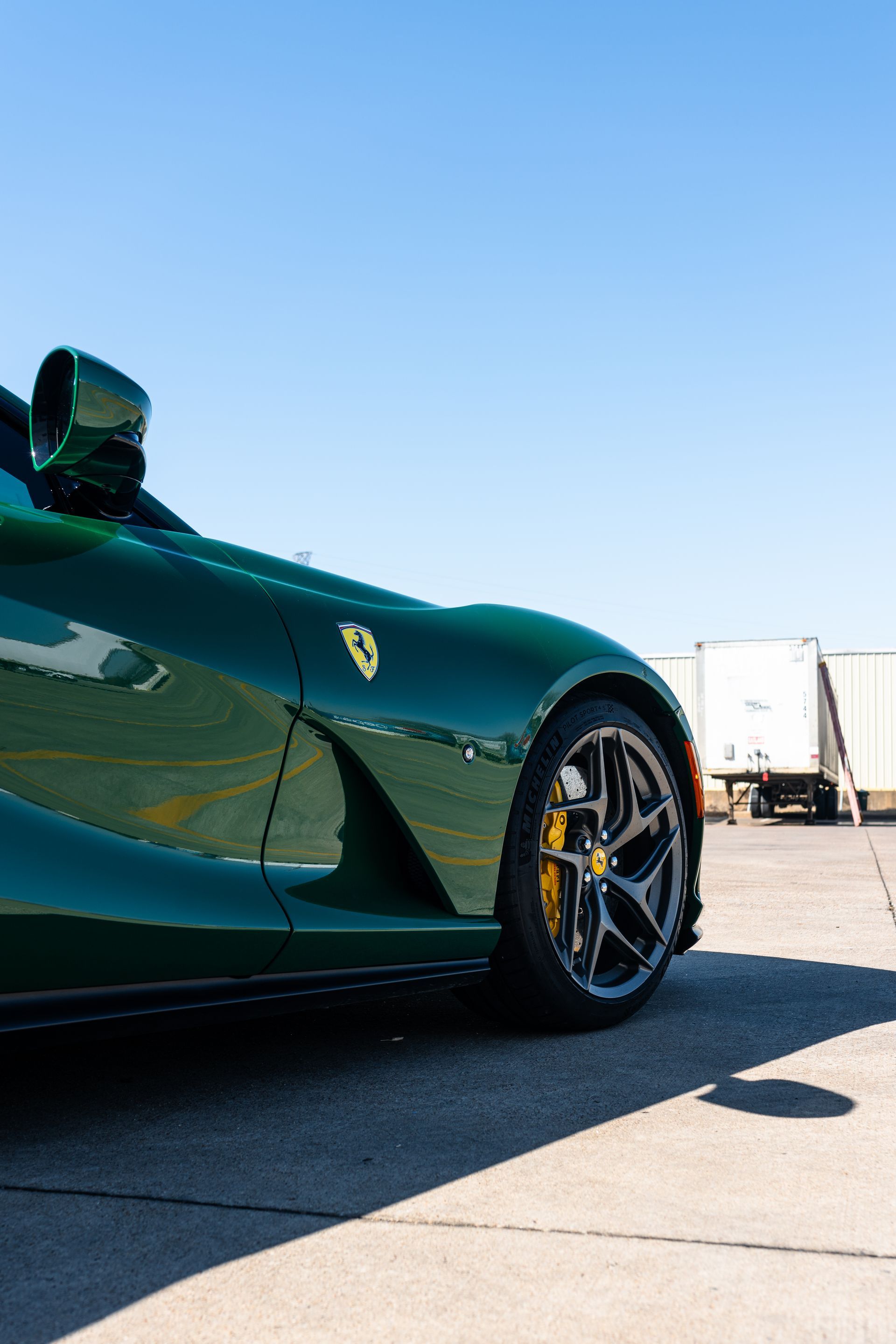 A green sports car is parked on the side of the road.