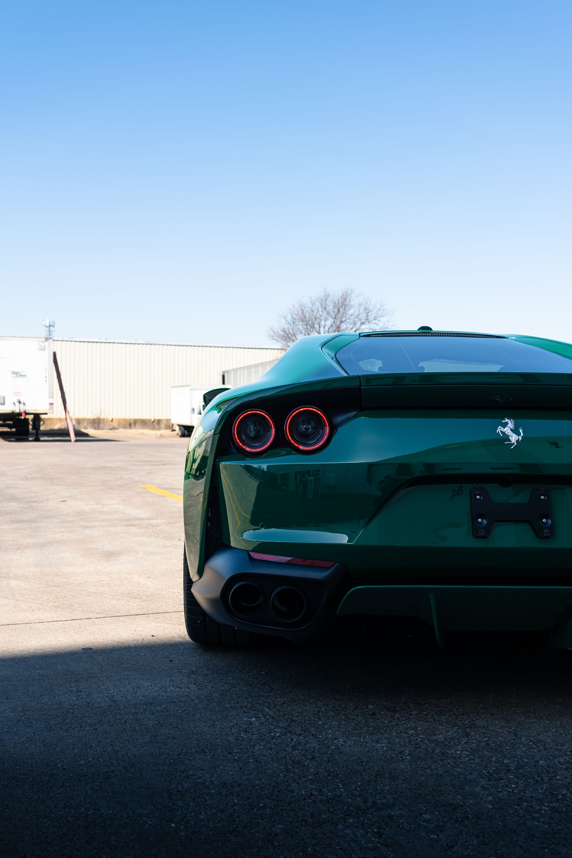 A green ferrari is parked in a parking lot.