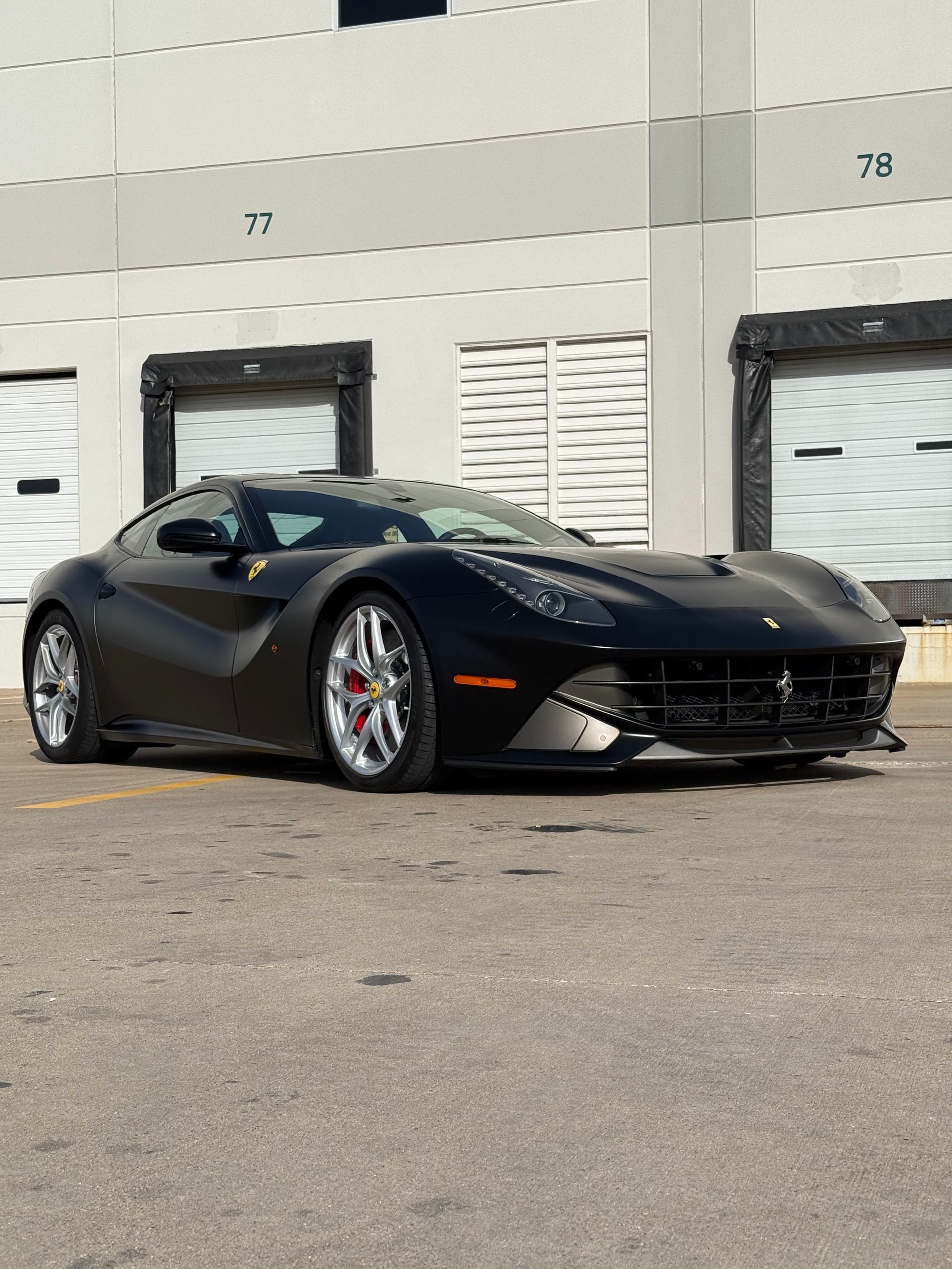 A black sports car is parked in front of a building.