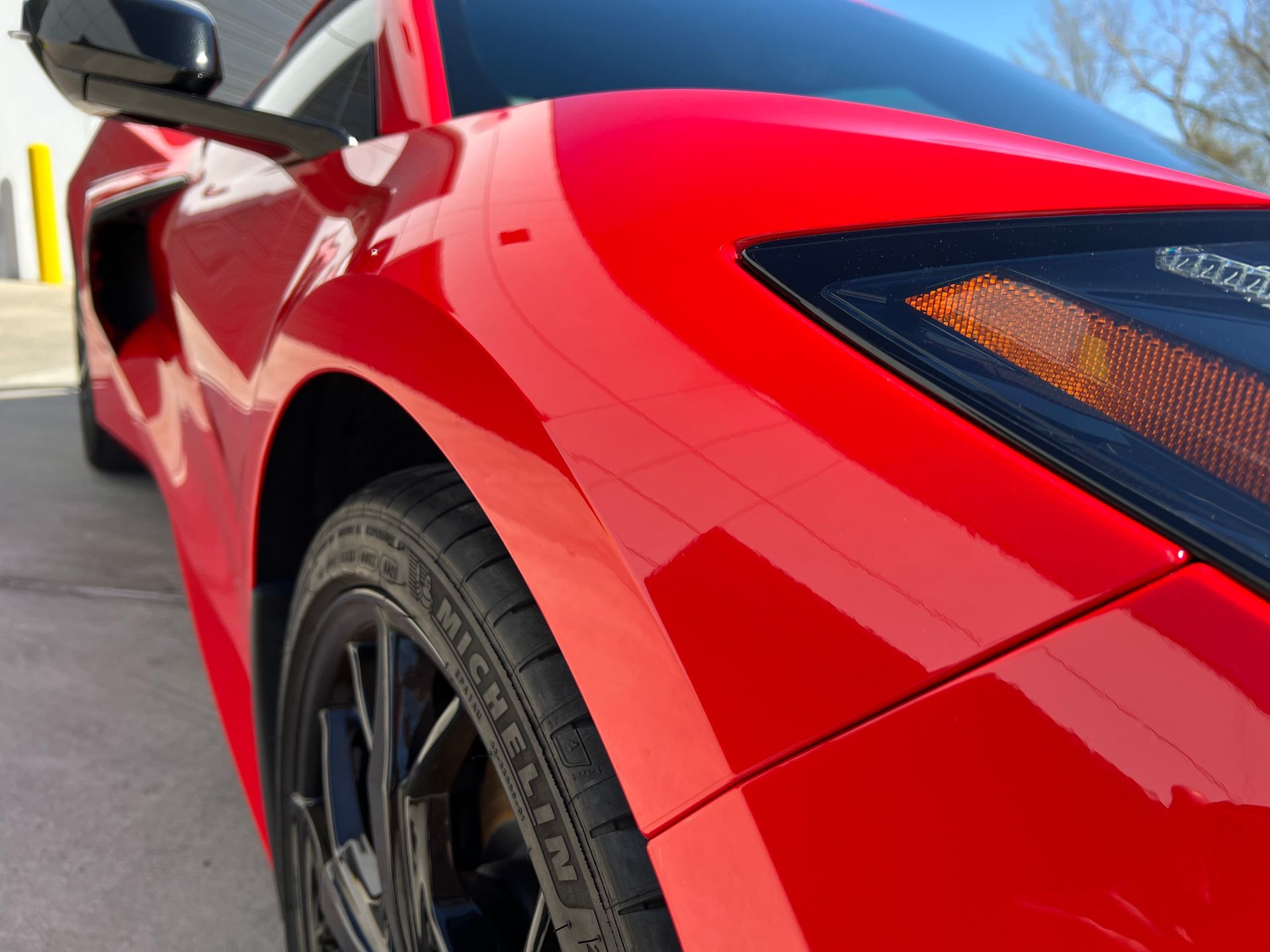 A red sports car is parked in a parking lot