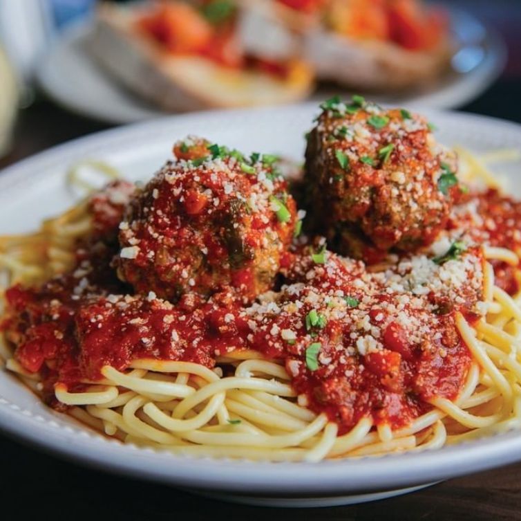 Spaghetti with meatballs, covered in red sauce and sprinkled with parmesan cheese.