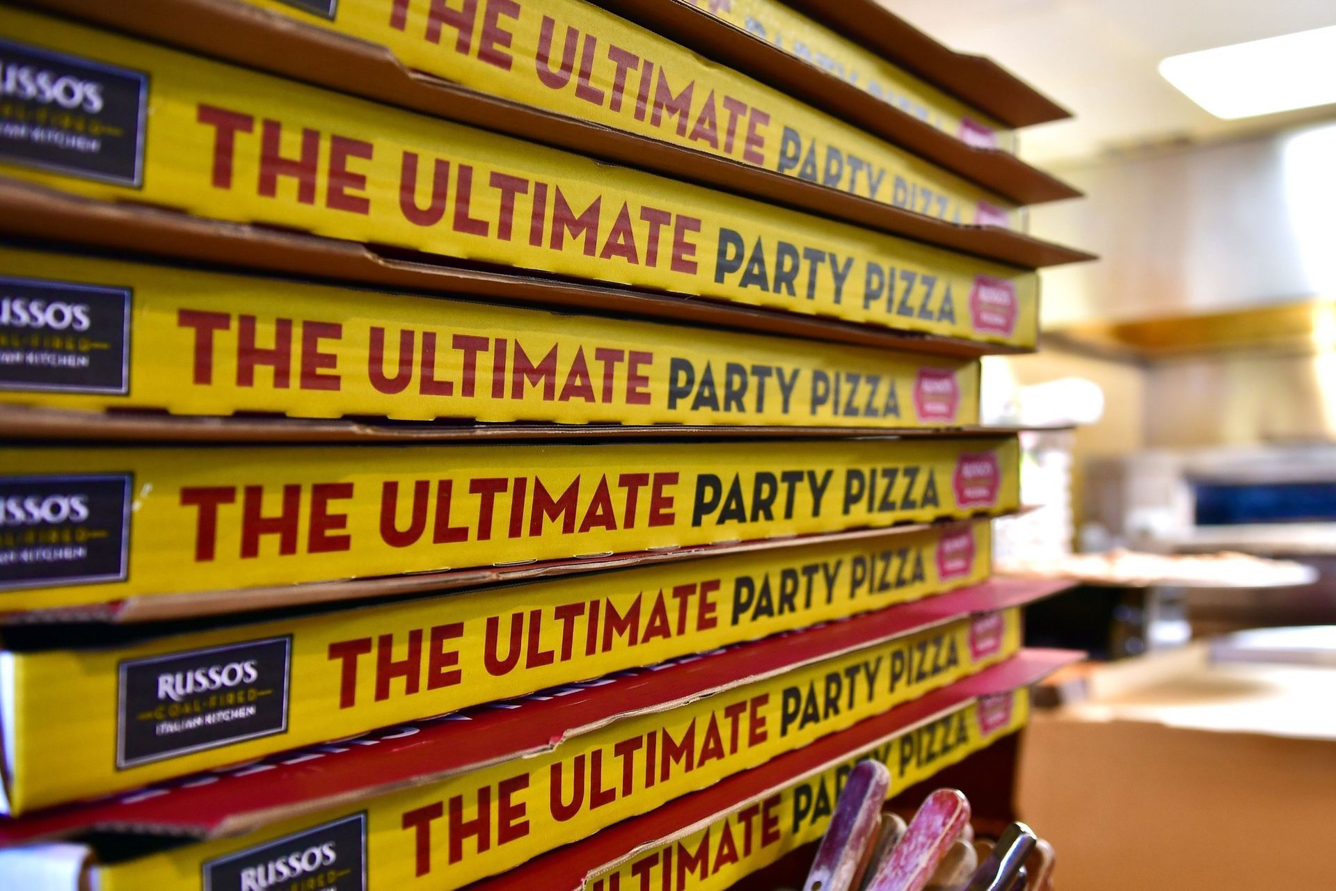A tall stack of yellow pizza boxes from Russo's New York Pizzeria, each labeled