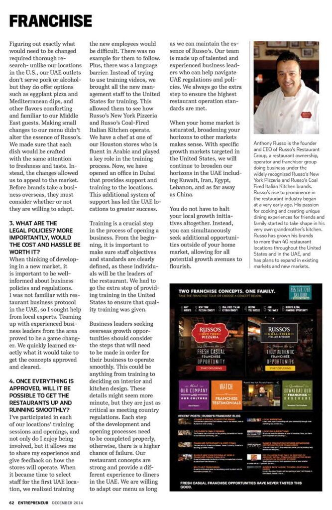 Man smiling at the camera, wearing a white shirt and a red apron.