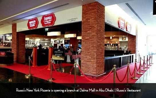 Exterior of Russo's New York Pizzeria at Dalma Mall, Abu Dhabi, with a red carpet entrance and brick column.