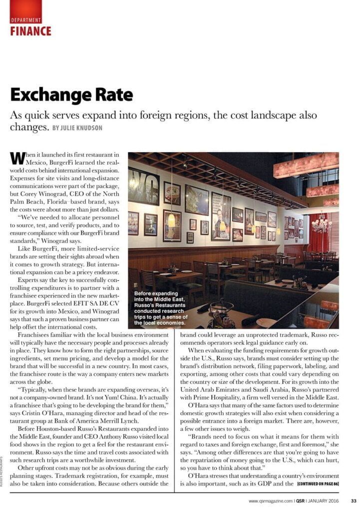 A restaurant interior with tables and chairs. Framed artwork hangs on the wall.