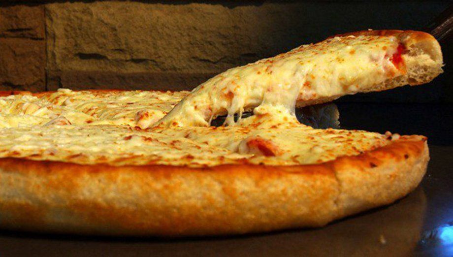 A slice of cheesy pizza being pulled from a whole pizza, with cheese stretching.
