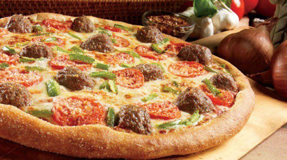 Pizza with meatballs, tomatoes, and green peppers.