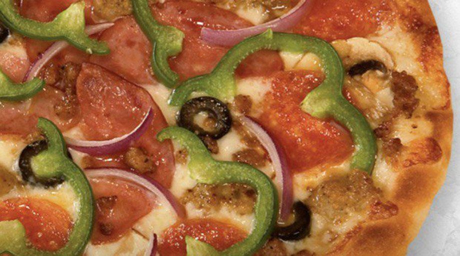 Close-up of pizza with pepperoni, green peppers, red onion, black olives, and sausage.