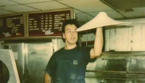 Pizza maker tossing dough high in the air.