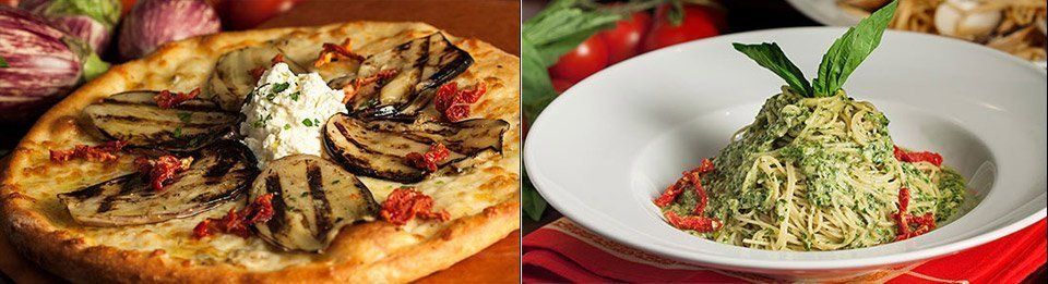 Two plates of food: a pizza with grilled vegetables and a pasta dish with pesto, garnished with basil.