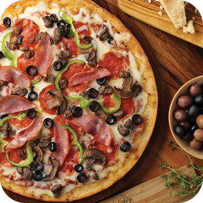 Pizza topped with pepperoni, ham, olives, mushrooms, and green peppers on a wooden surface, with a bowl of olives and parmesan cheese.