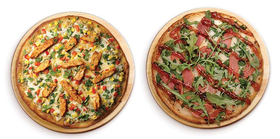 Two pizzas on wooden boards, one with chicken and vegetables, the other with prosciutto and arugula.