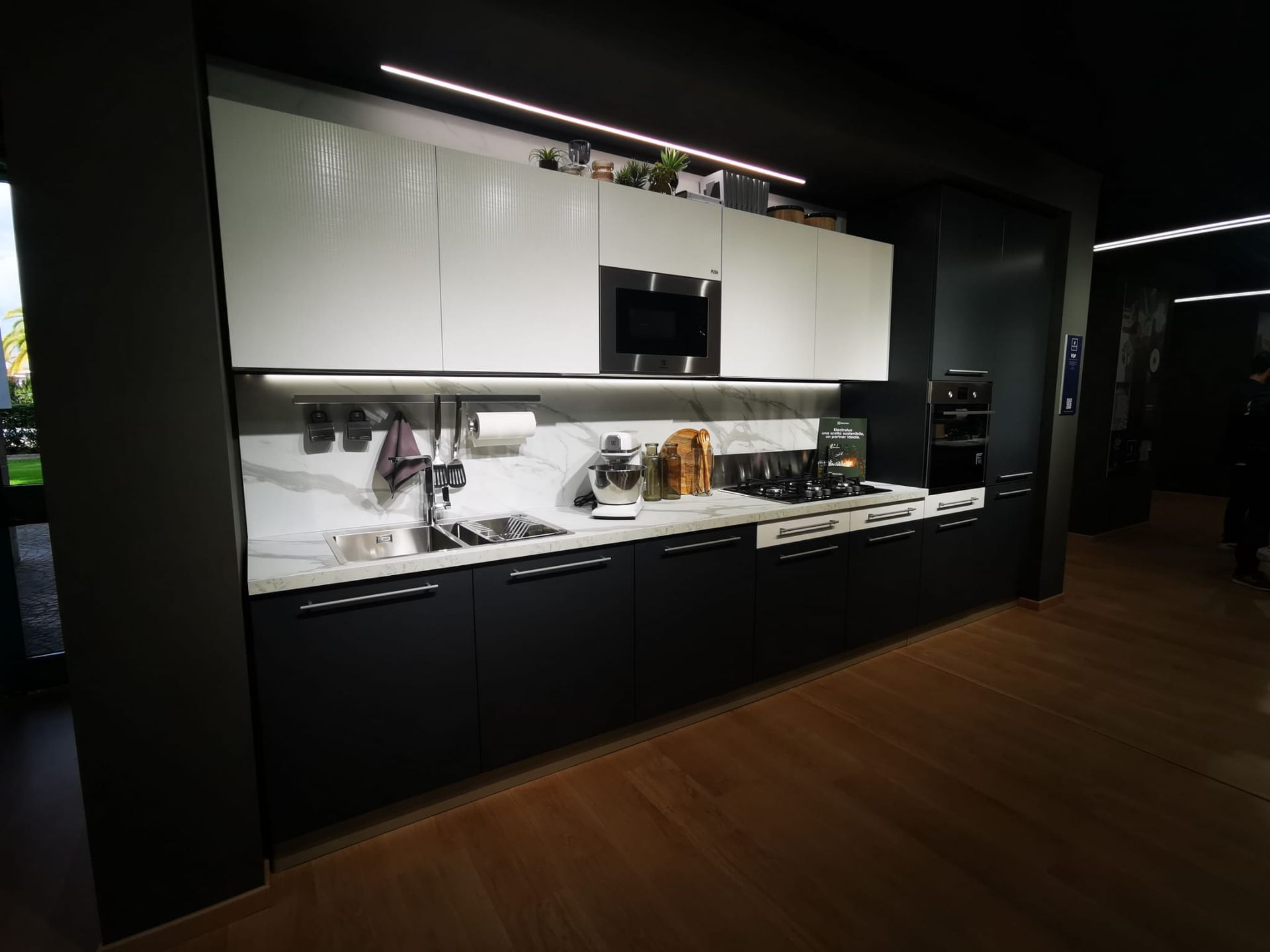 Una cucina con mobili bianchi e neri e pavimento in legno.