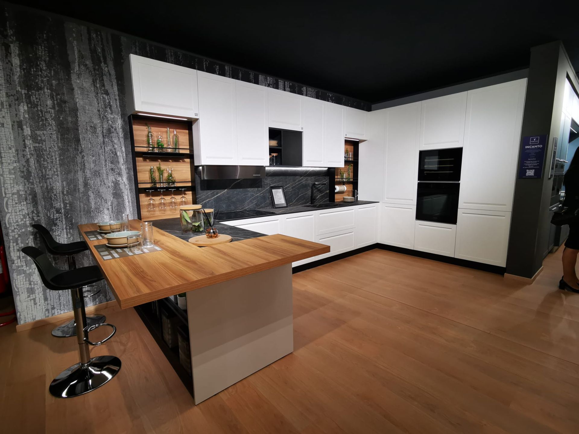 Una cucina con mobili bianchi e ripiano in legno.