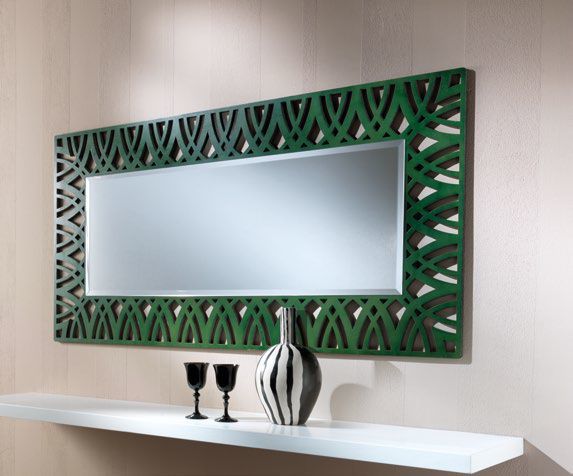 Uno specchio con cornice verde è appeso a una parete