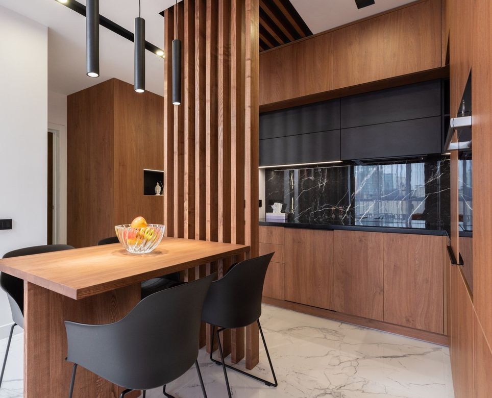 A kitchen with a wooden table and chairs and a bowl of fruit on it.